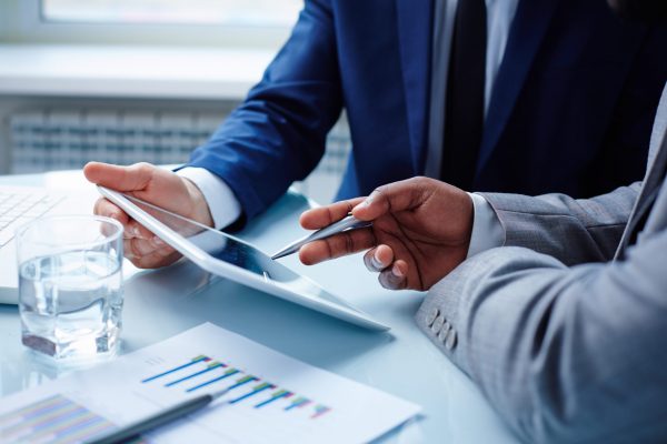 Image of businessmen discussing data in touchpad at meeting